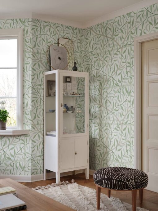 a white cabinet with a zebra stool in a room with green wallpaper
